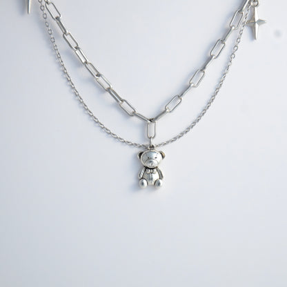 Silver chain charm necklace with a teddy bear pendant on a white background