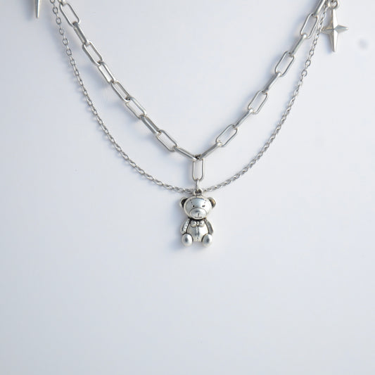 Silver chain charm necklace with a teddy bear pendant on a white background