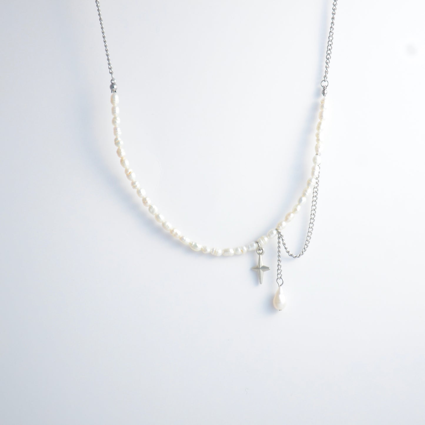 Pearl choker necklace with a small star pendant and a layering chain with pearl on a light gray background