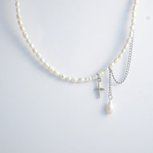 Pearl choker necklace with a small star pendant and a layering chain with pearl on a light gray background
