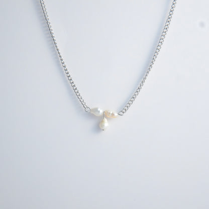 Silver necklace non-tarnish with three pearl beads on a light gray background