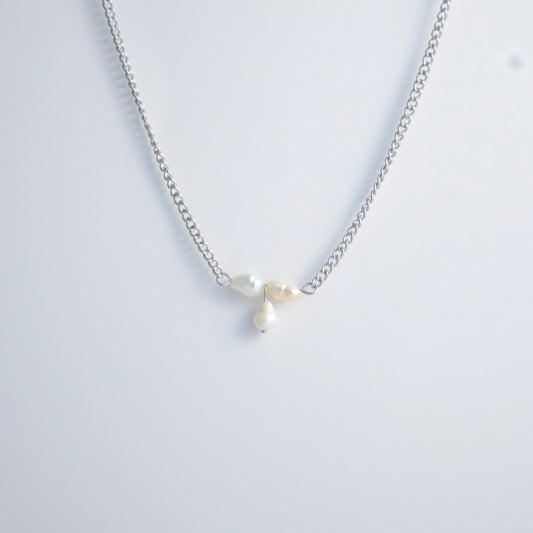 Silver necklace non-tarnish with three pearl beads on a light gray background