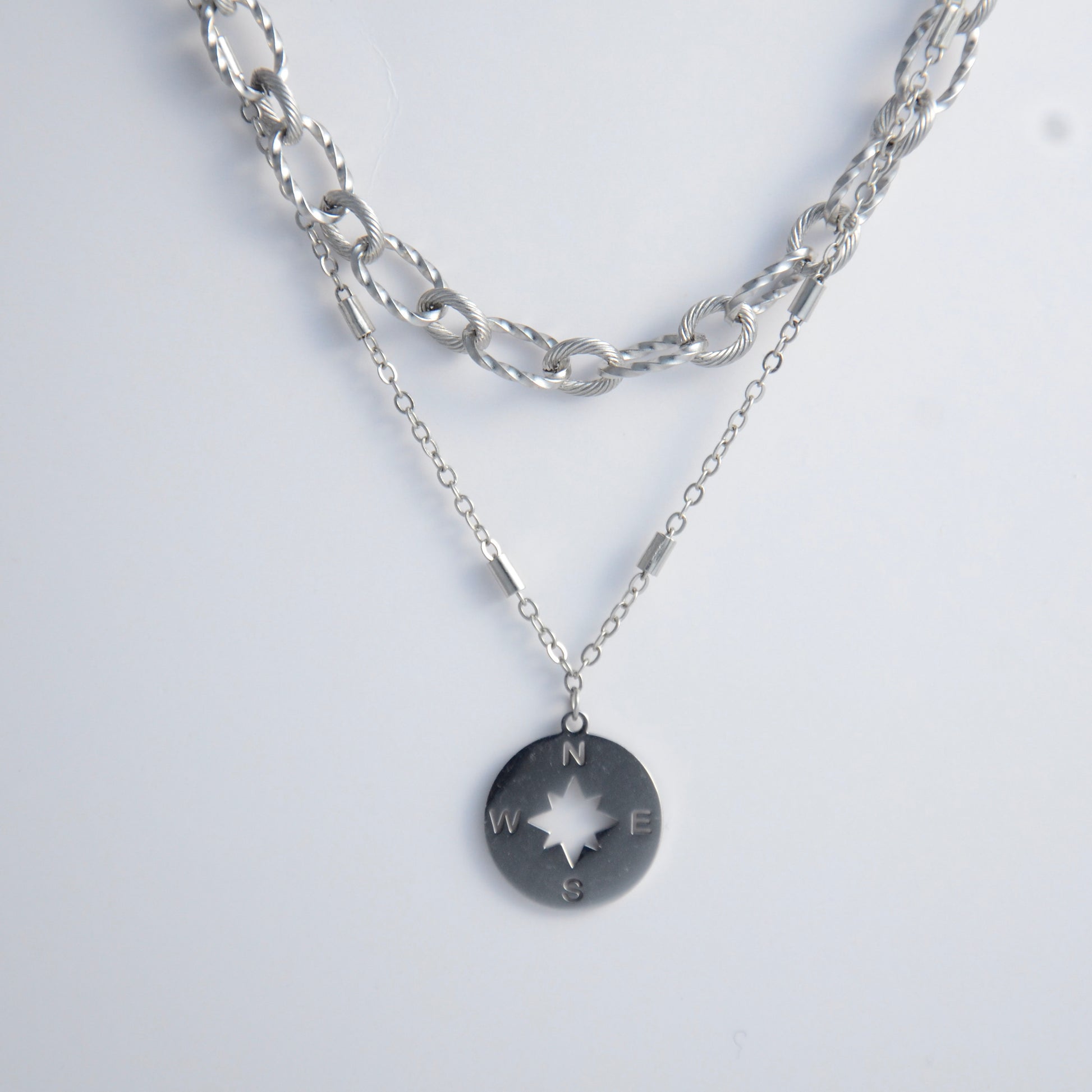 Silver layered paperclip necklaces non-tarnish with compass charm on a light gray background