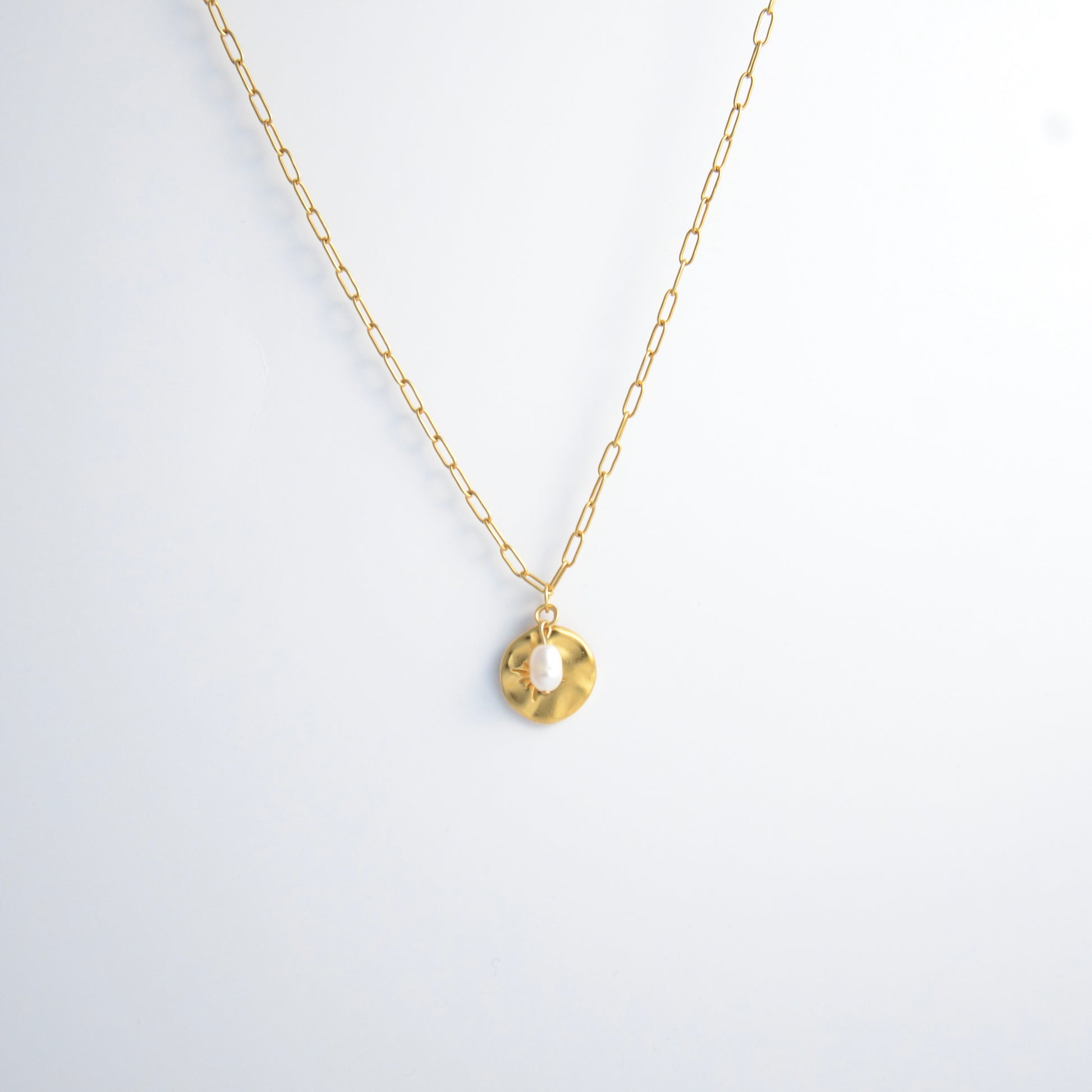 Gold paperclip necklace non-tarnish with a round sun pendant and a pearl on a light gray background
