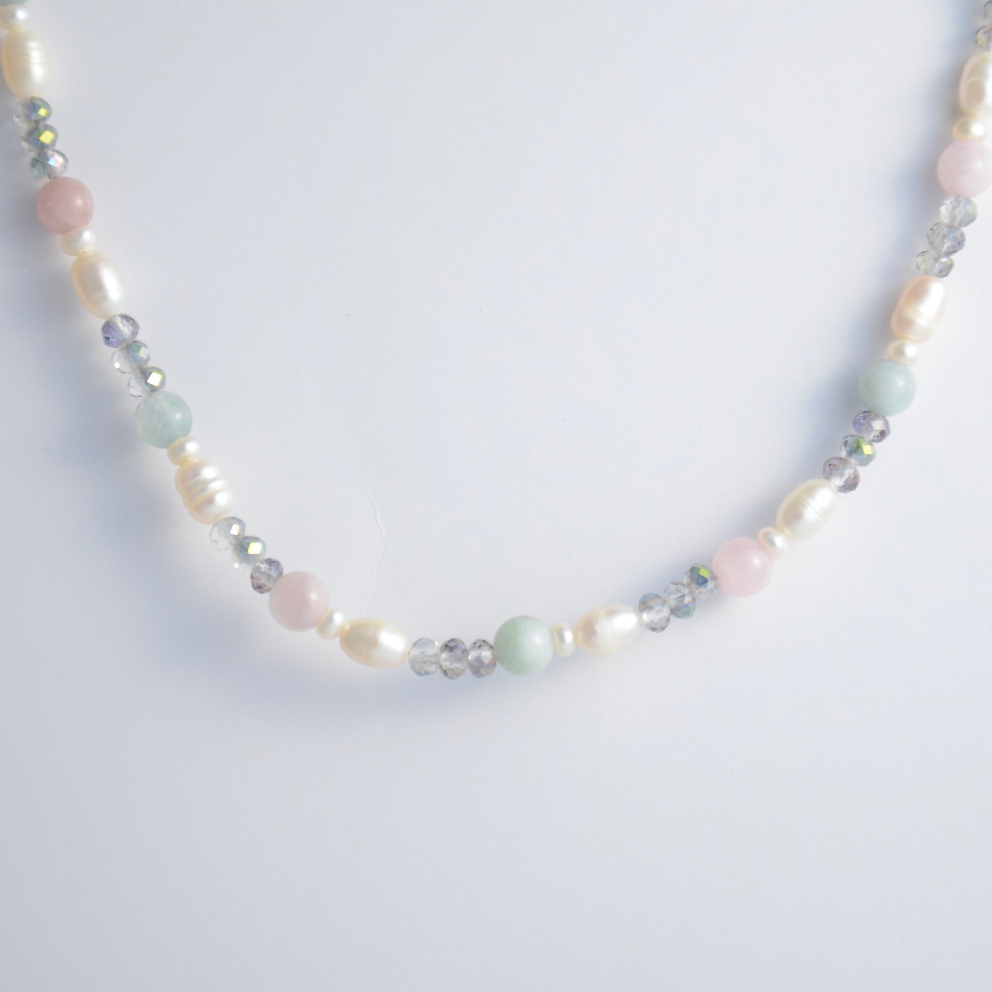 Beaded necklace with pearls and glass beads on a light gray background