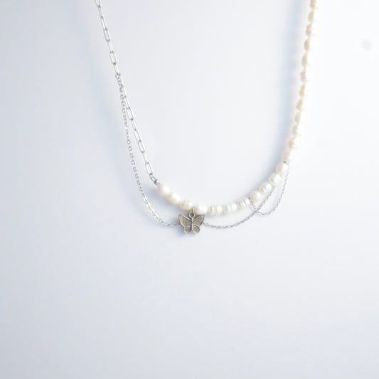 Silver necklace non-tarnish with pearl strands, layered chains and a silver butterfly pendant on a light gray background