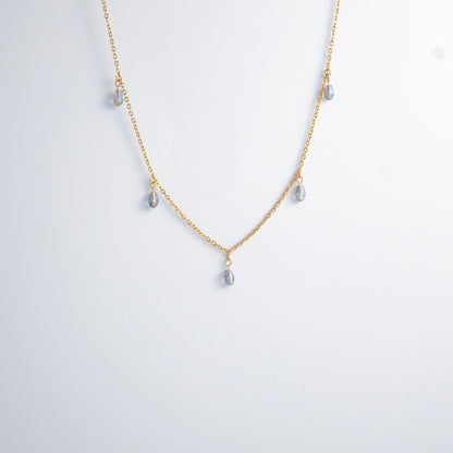 Gold satellite necklace with small purple glass beads on a light gray background