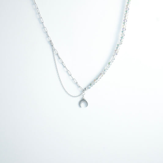 Silver layered necklace with a moon pendant and glass beads on a paperclip chain on a light gray background
