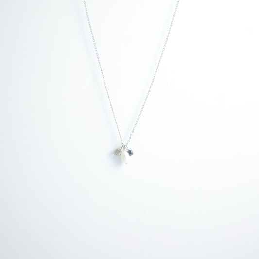 Silver dainty necklace with three small charms made of glass beads and pearls on a white background
