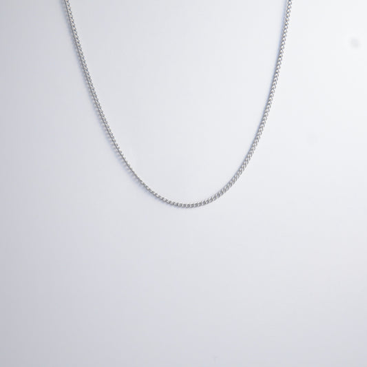 Dainty silver curb chain for minimalistic fashion or for layering jewelry on a light gray background