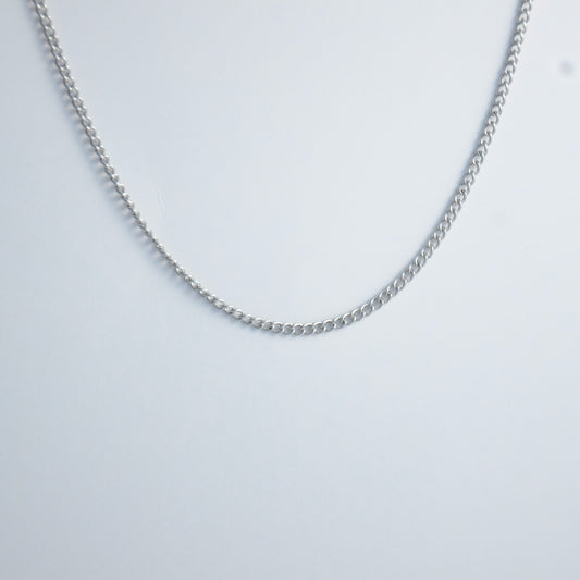 Dainty silver curb chain for minimalistic fashion or for layering jewelry on a light gray background