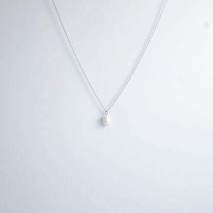 Silver dainty pearl necklace with freshwater pearl charm on a light gray background