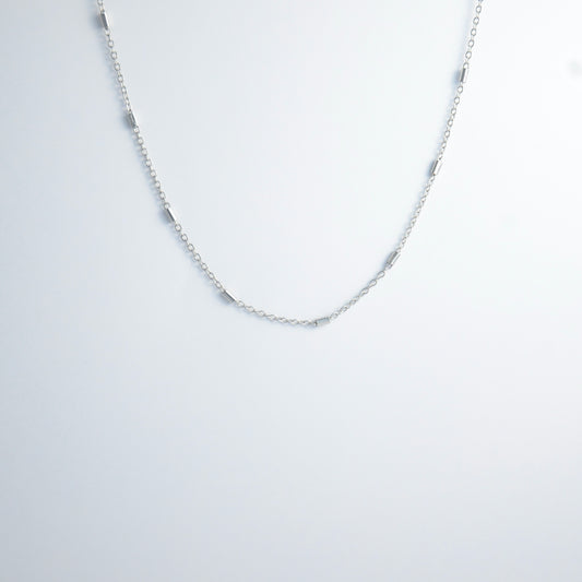 Dainty silver bar link chain for minimalistic fashion or for layering jewelry on a light gray background