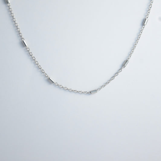 Dainty silver bar link chain for minimalistic fashion or for layering jewelry on a light gray background