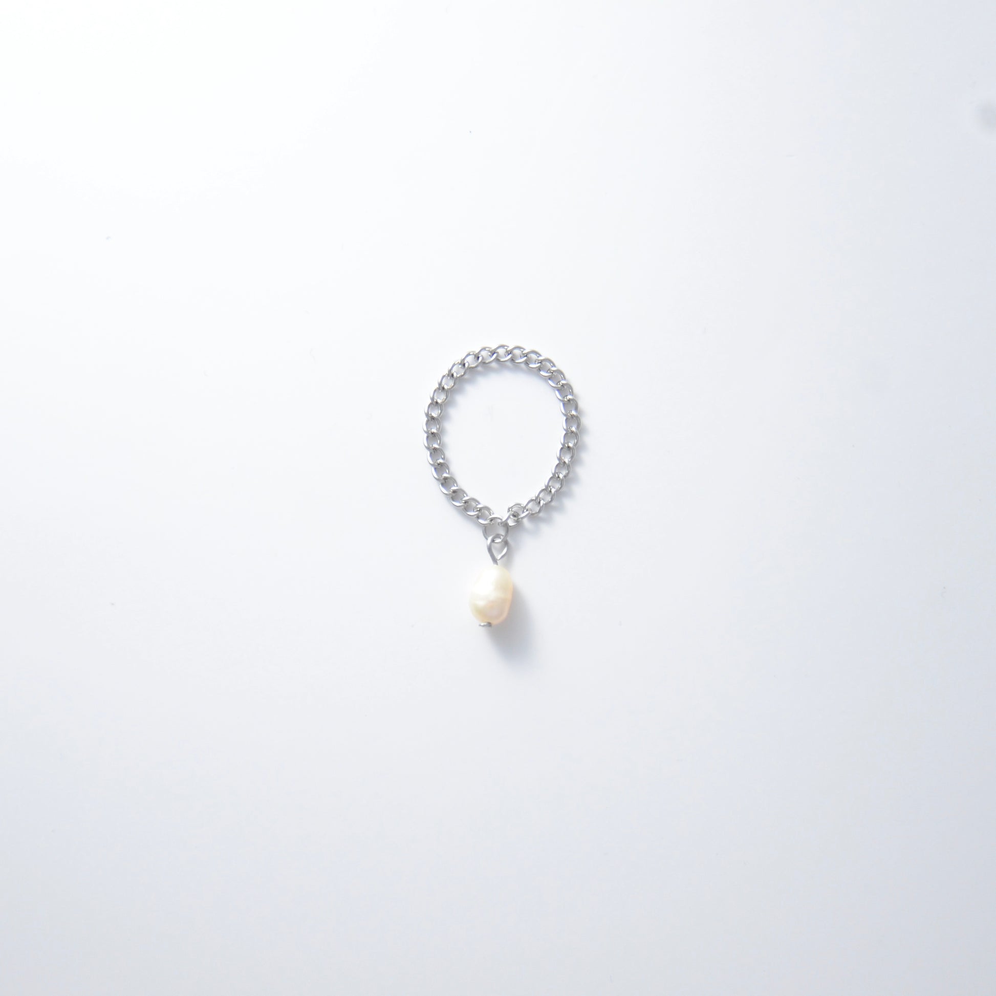Silver stainless steel curb chain ring with a pearl charm on a white background