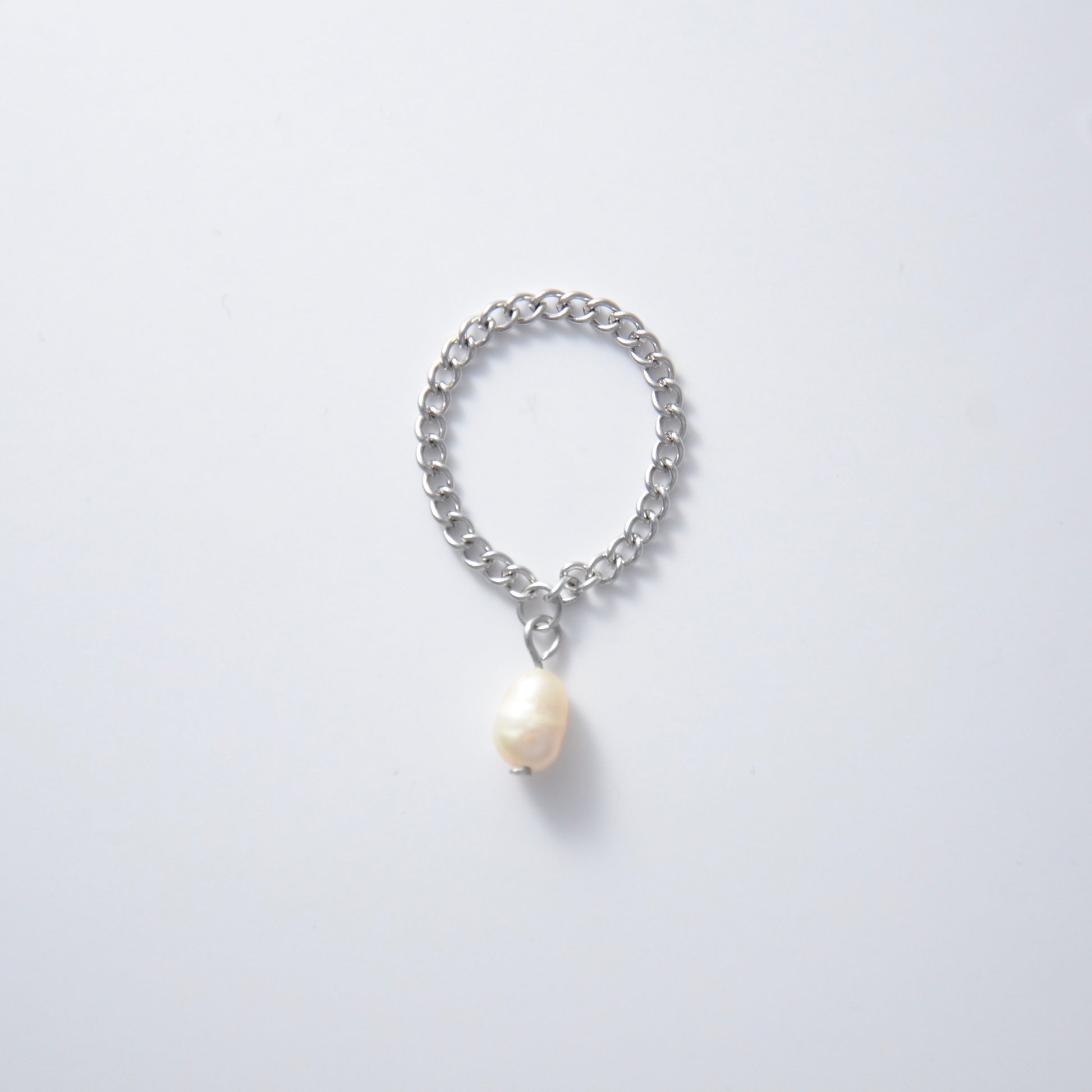 Silver stainless steel dainty chain ring with a pearl charm on a white background