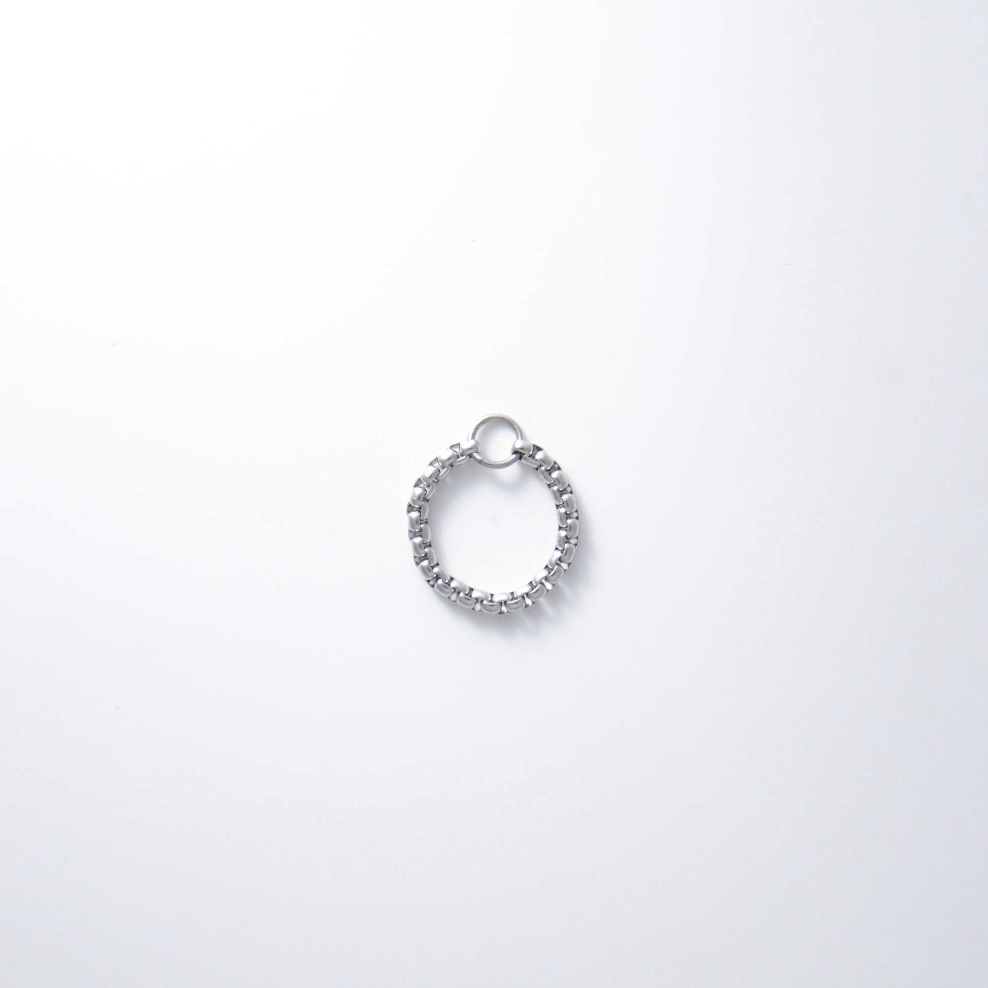 Silver stainless steel box chain ring on a light gray background non-tarnish geometric shape