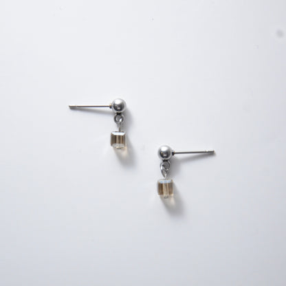 Pair of silver stainless steel ball stud earrings with sugar cube gray glass beads on a white background