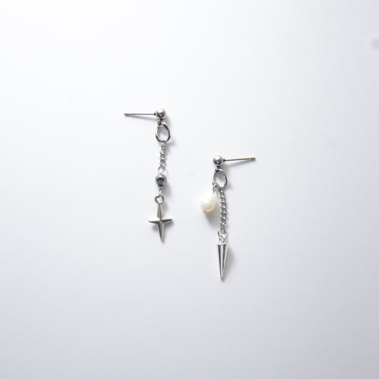 Pair of silver stainless steel ball stud drop earrings with a chain and star charm and a pearl and spike charm on a white background