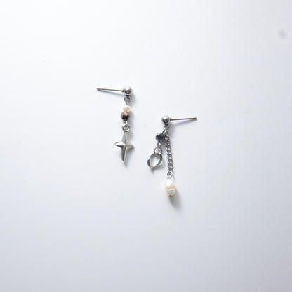 Pair of silver stainless steel ball stud drop earrings with orange and black glass beads and star and pearl charm with unique designs on a white background