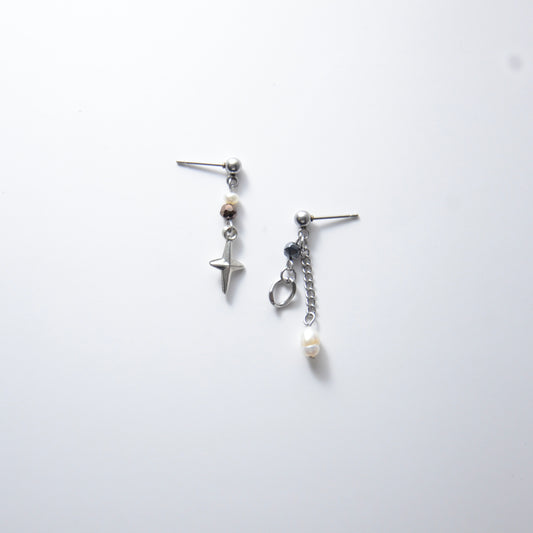 Pair of silver stainless steel ball stud drop earrings with orange and black glass beads and star and pearl charm with unique designs on a white background