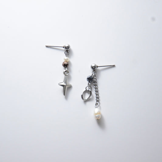 Pair of silver stainless steel ball stud drop earrings with orange and black glass beads and star and pearl charm with unique designs on a white background