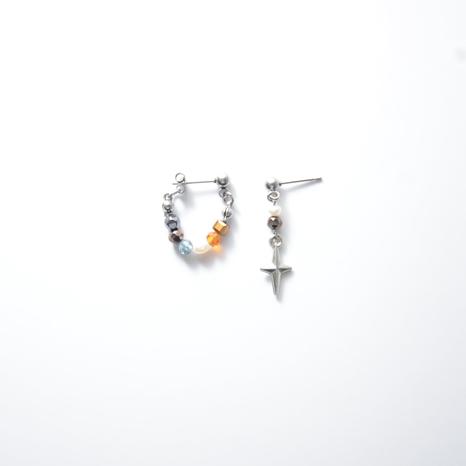 Pair of stainless steel hoop earrings with small beads and drop earrings with star charm on a white background