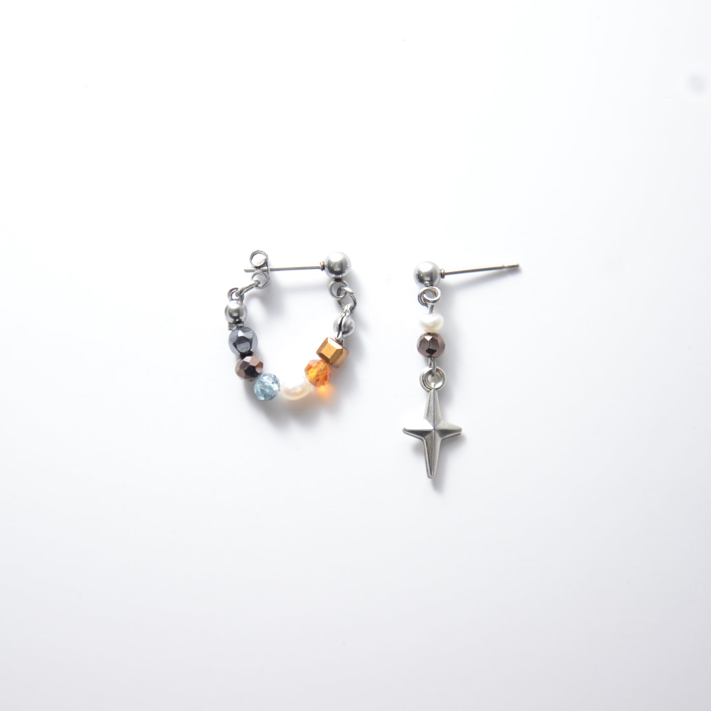Pair of stainless steel hoop earrings with small beads and drop earrings with star charm on a white background