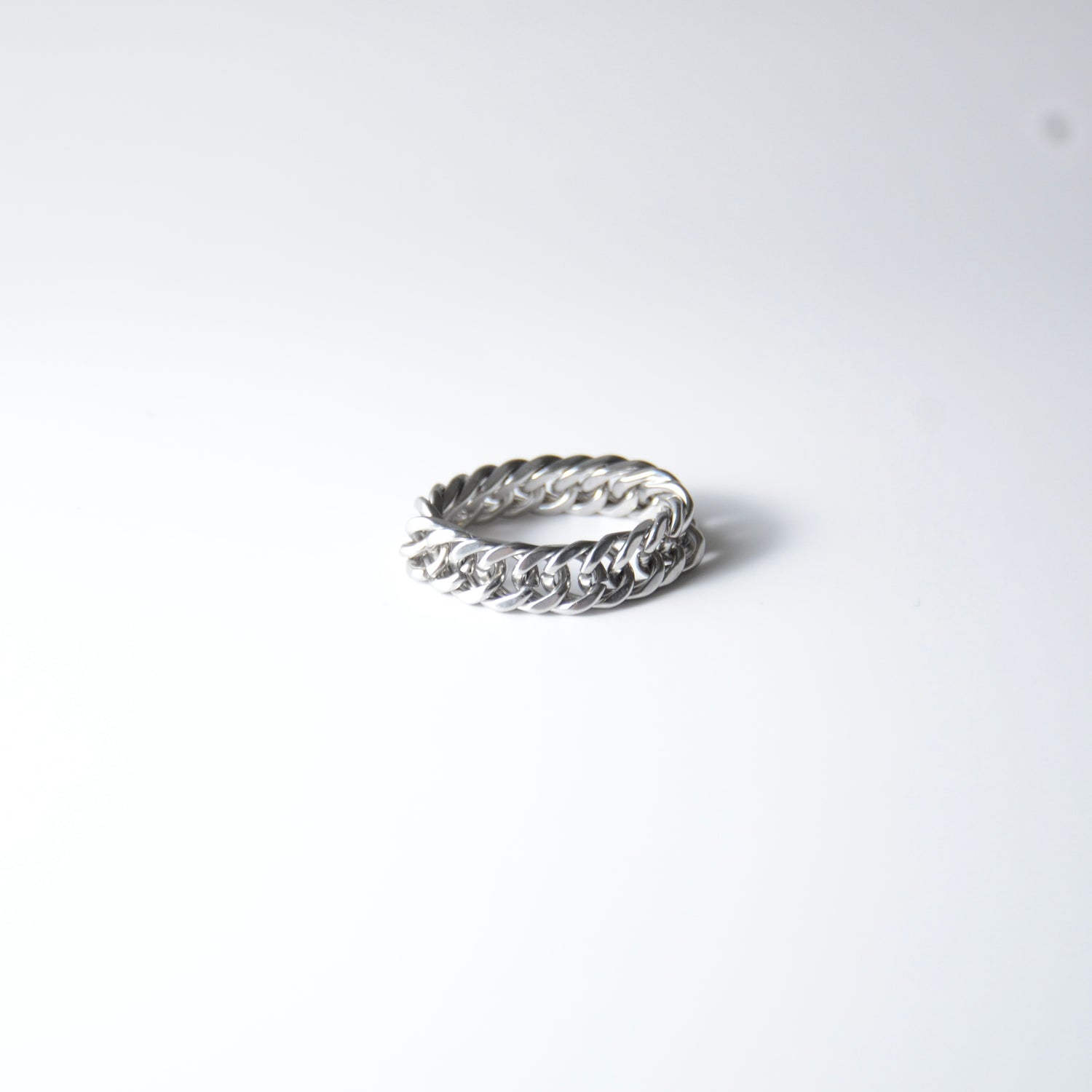 Silver braided cuban chain stainless steel ring on a white background