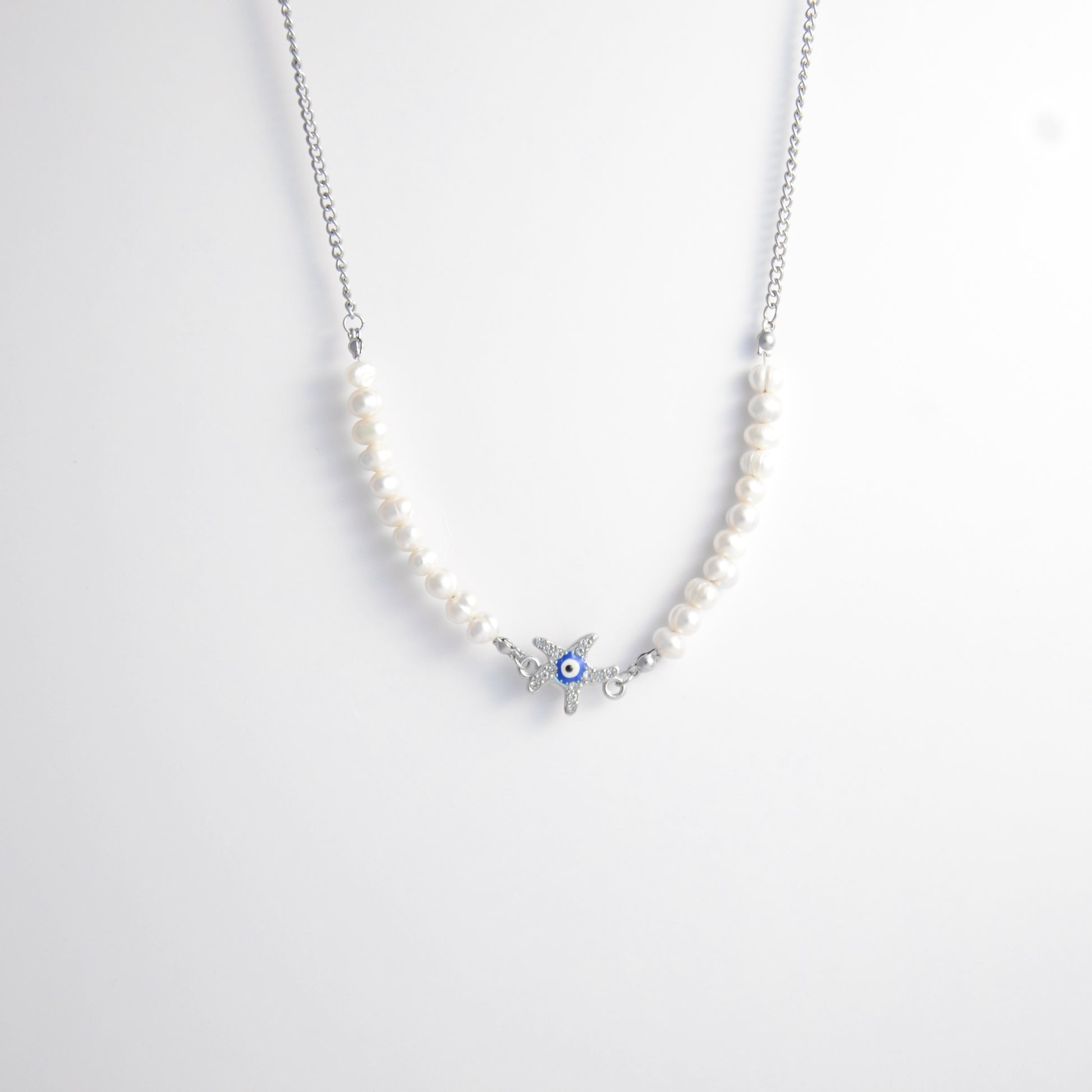 Silver stainless steel pearl choker necklace with a silver star evil eye pendant on a light gray background