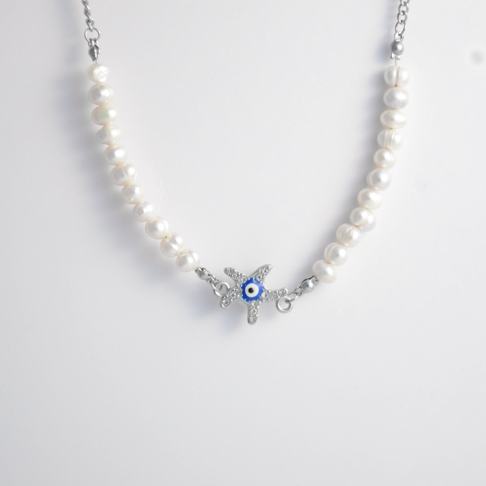 Silver stainless steel pearl choker necklace with a silver star evil eye pendant on a light gray background