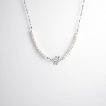 Silver stainless steel pearl choker necklace with a silver dragonfly evil eye pendant on a light gray background