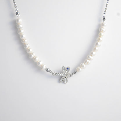Silver stainless steel pearl choker necklace with a silver dragonfly evil eye pendant on a light gray background