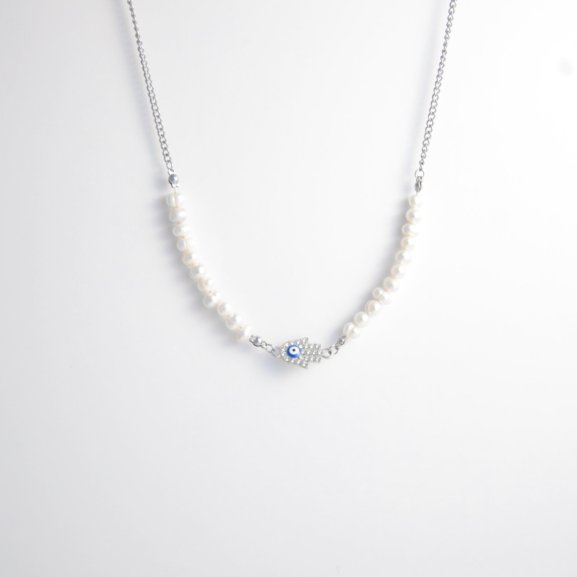 Silver stainless steel pearl choker necklace with a silver hand evil eye pendant on a light gray background
