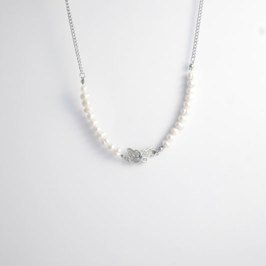 Silver stainless steel pearl choker necklace with a silver butterfly evil eye pendant on a light gray background
