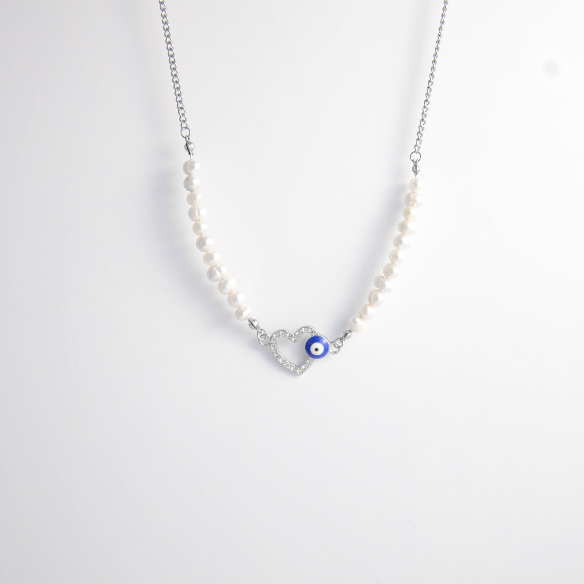 Silver stainless steel pearl choker necklace with a silver heart evil eye pendant on a light gray background