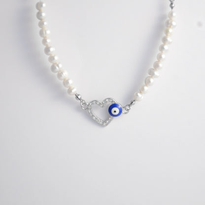 Silver stainless steel pearl choker necklace with a silver heart evil eye pendant on a light gray background