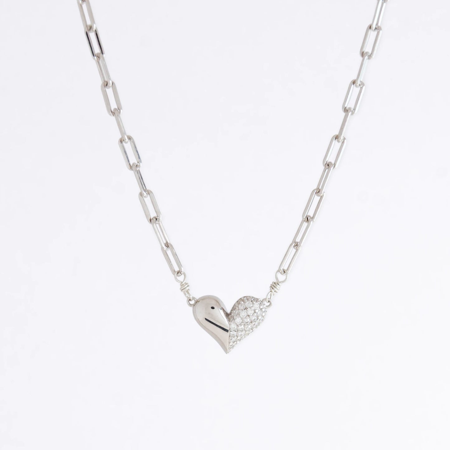 Silver heart-shaped pendant necklace on a light gray background