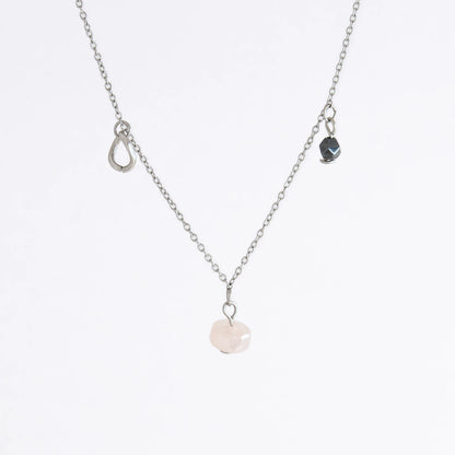 Silver stainless steel delicate charm necklace with small pink, black, purple glass beads and a geometric charm on a light gray background