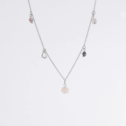 Silver stainless steel delicate charm bracelet with small pink, black, purple glass beads and a geometric charm on a light gray background