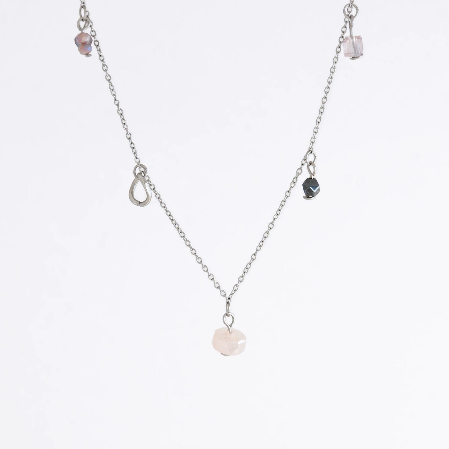 Silver stainless steel delicate charm bracelet with small pink, black, purple glass beads and a geometric charm on a light gray background