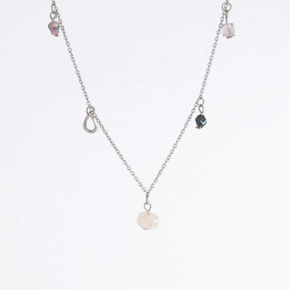 Silver stainless steel delicate charm bracelet with small pink, black, purple glass beads and a geometric charm on a light gray background
