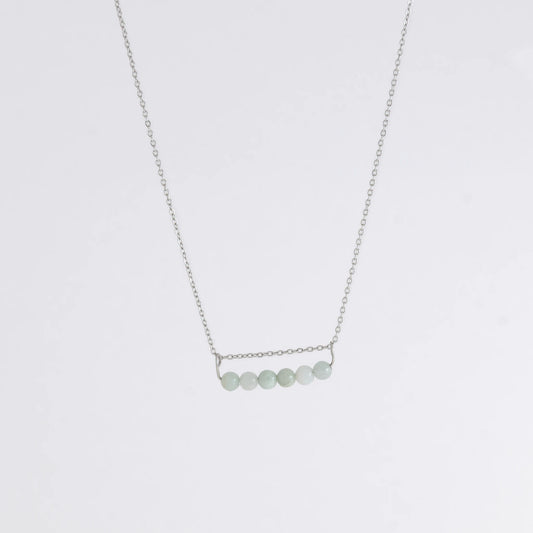Silver necklace with a pendant made of jade beads on a light gray background
