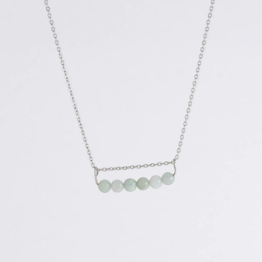 Silver necklace with a pendant made of jade beads on a light gray background