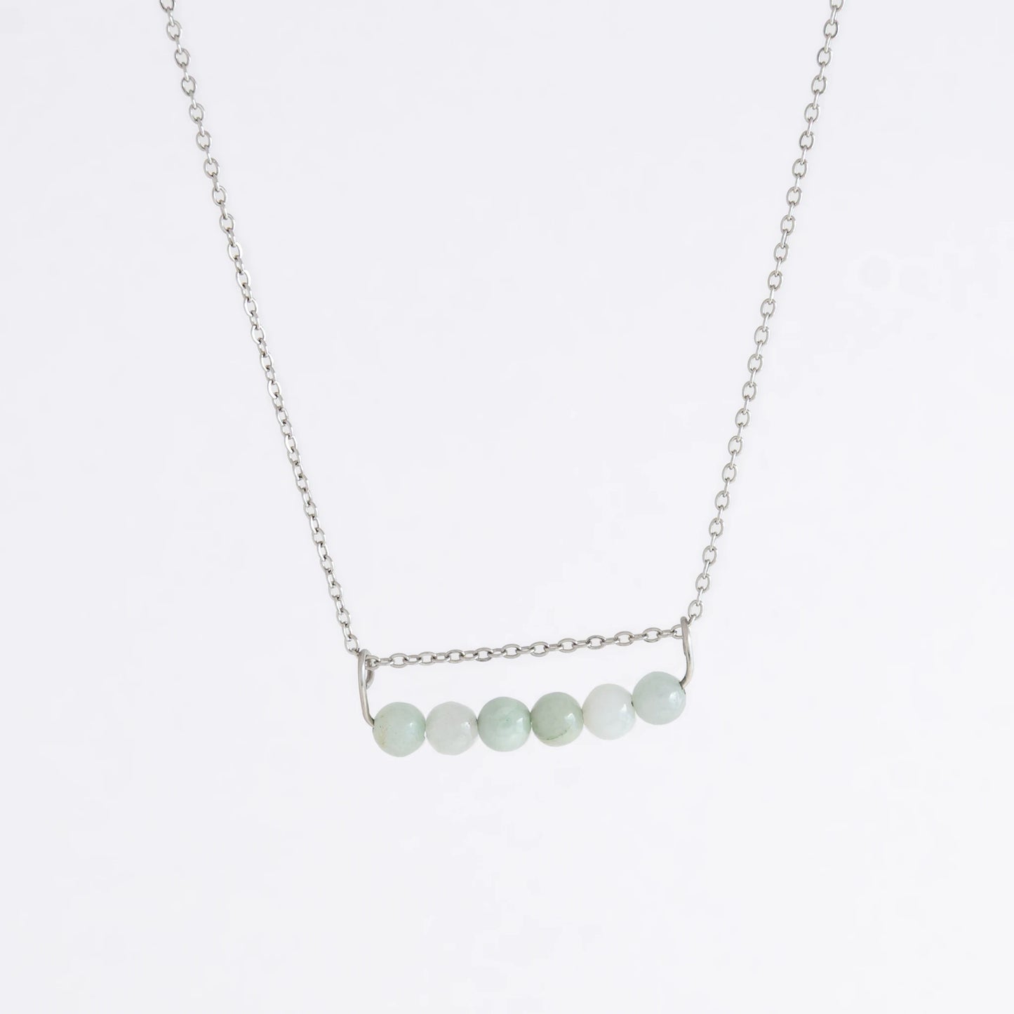 Silver necklace with a pendant made of jade beads on a light gray background