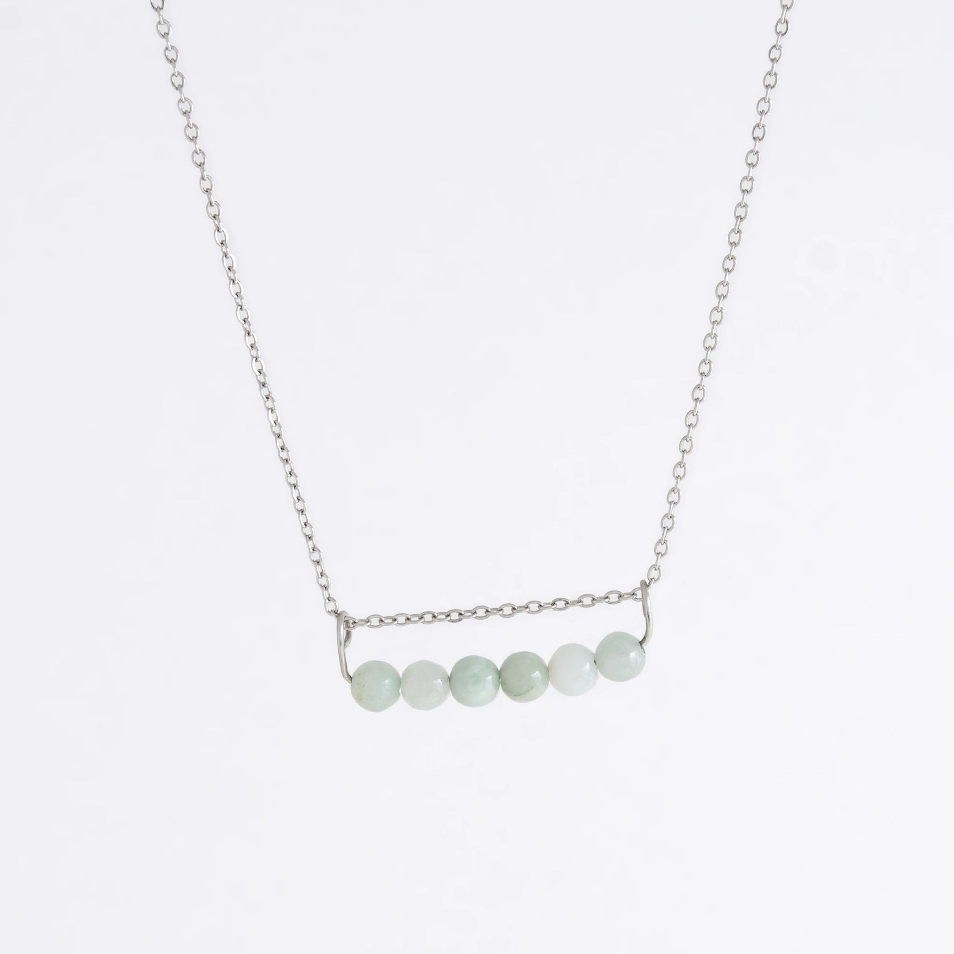 Silver necklace with a pendant made of jade beads on a light gray background