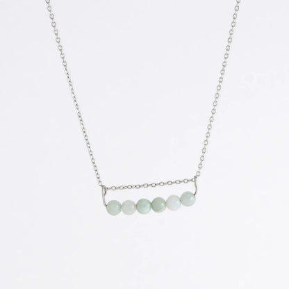 Silver necklace with a pendant made of jade beads on a light gray background