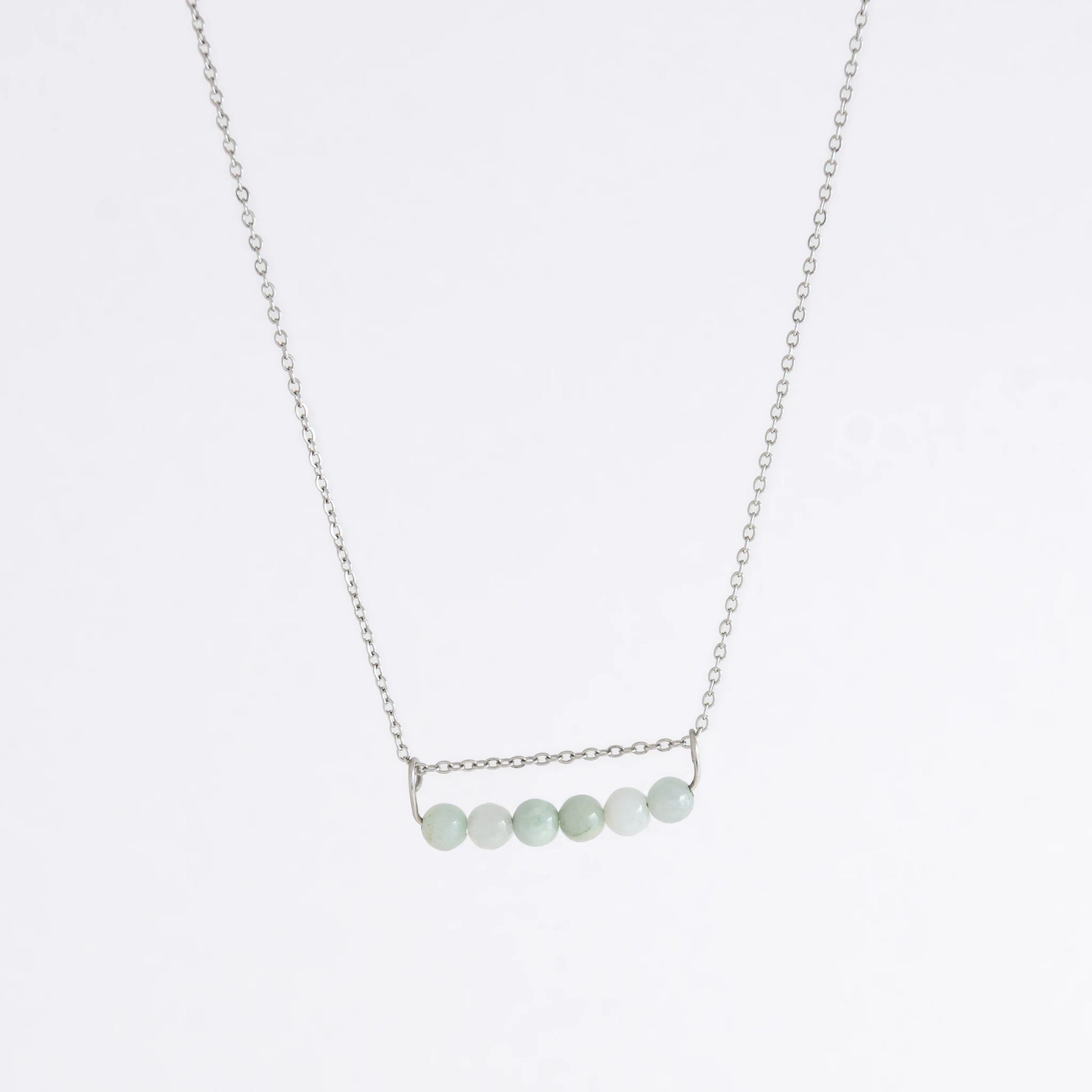 Silver necklace with a pendant made of jade beads on a light gray background