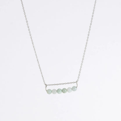 Silver necklace with a pendant made of jade beads on a light gray background