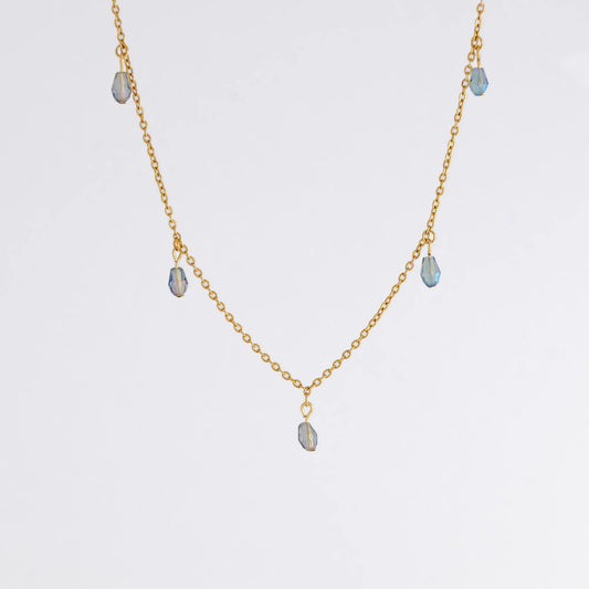 Gold satellite necklace with small purple glass beads on a light gray background
